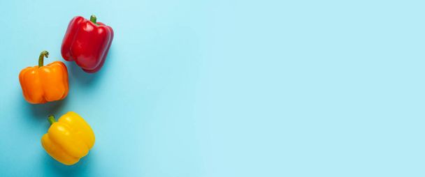 Mavi arka planda üç taze, parlak biber. Üst manzara, düz yatış. Pankart - Fotoğraf, Görsel
