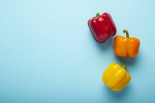 Three fresh bright sweet peppers on a blue background. Top view, flat lay.  - Foto, imagen