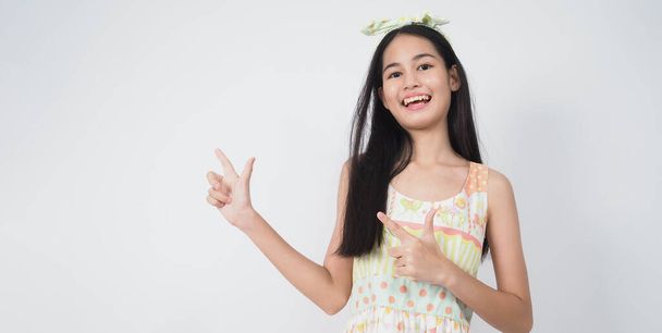 Aziatisch Jonge vrouw gebaar poseren op witte achtergrond. vertegenwoordigen vrolijk en zelfverzekerd. Toont gebaren zoals mini hart Okay Thumb up of wijzen op. Blij verbaasd opgewonden en verrast. Leuk meisje in jurk.  - Foto, afbeelding