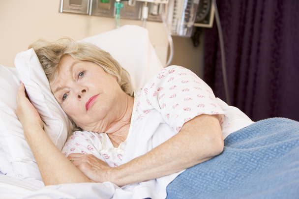 Senior Woman Lying In Hospital Bed - 写真・画像