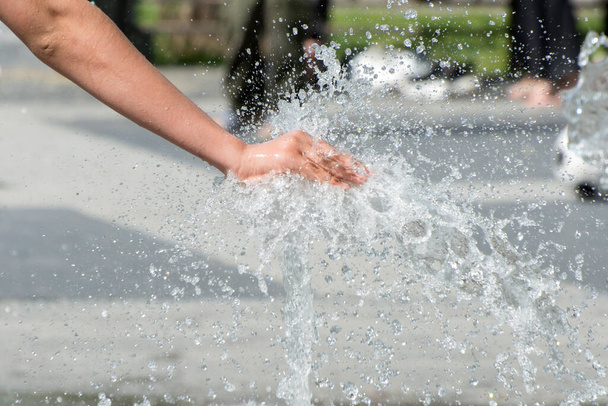 Dětská ručička se koupe ve fontáně v městském parku. Šťastné dětství. Mezinárodní den dětí. - Fotografie, Obrázek