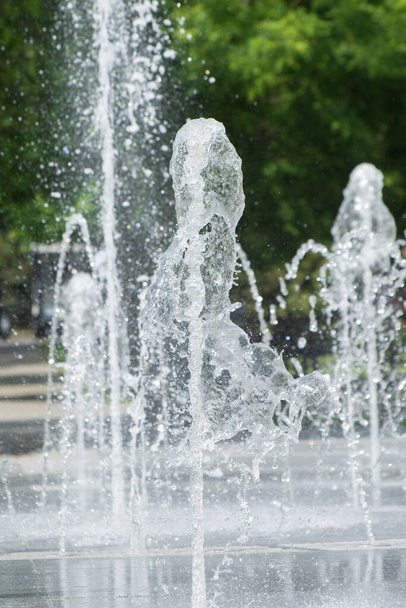 Water jets and spray of a fountain in a city park. Background from drops of water. - Photo, Image