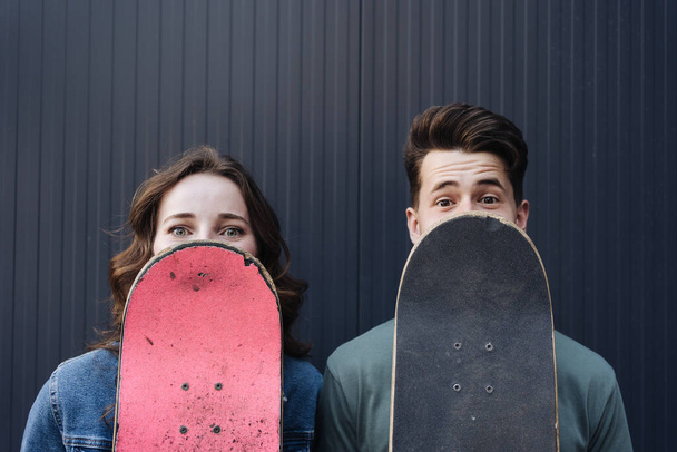 Moderne glimlachende paar staan samen met skateboards - Foto, afbeelding