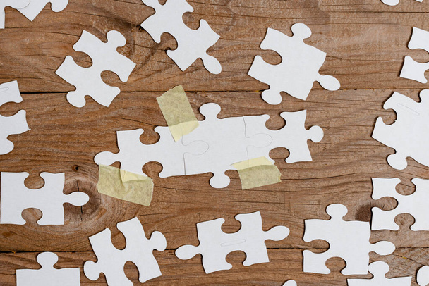 Close-Up White Jigsaw Pattern Puzzle Piezas que se conectarán con faltante última pieza colocada en un fondo plano con diferentes accesorios de textura y papel - Foto, imagen