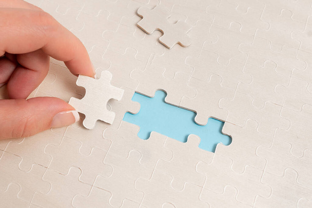 Close-Up bianco puzzle modello pezzi da collegare con mancante ultimo pezzo posizionato su uno sfondo piatto laico con texture diversa e forniture di carta accessori - Foto, immagini