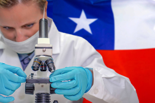 Biochemička se dívá skrz mikroskop na pozadí chilské vlajky. Lékařská technologie a farmaceutický výzkum a vývoj vědecké koncepce v Chile - Fotografie, Obrázek