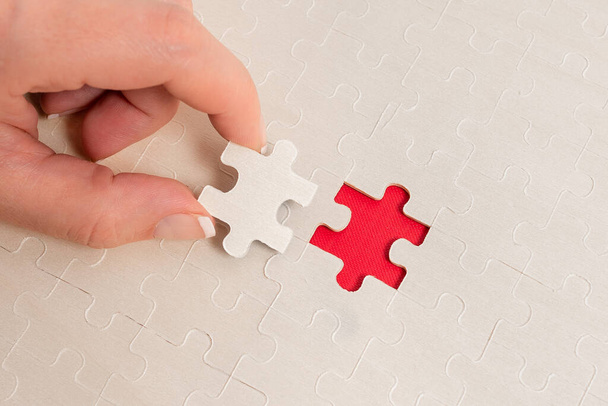 Close-Up White Jigsaw Pattern Puzzle Pieces To Be Connected With Missing Last Piece Positioniert auf einem flachen Hintergrund mit unterschiedlicher Textur und Papierzubehör Zubehör - Foto, Bild