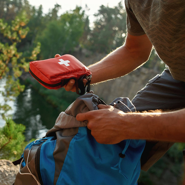 Young man taking out first aid kit from backpack - Fotoğraf, Görsel