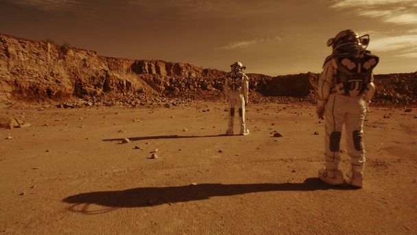 Нерозпізнані астронавти стоять проти гір на Марсі. - Фото, зображення