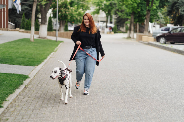 Donna che cammina, discute e gioca con il suo animale domestico dalmata in città - Foto, immagini