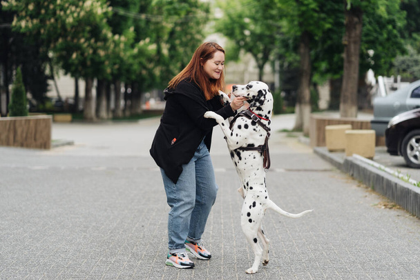 Woman discussing and training her dalmatian pet in the city - Fotó, kép