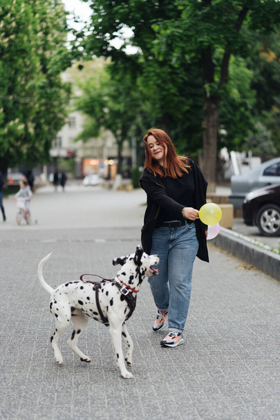 Kobieta dyskutująca i szkoląca swojego dalmatyńskiego zwierzaka w mieście - Zdjęcie, obraz