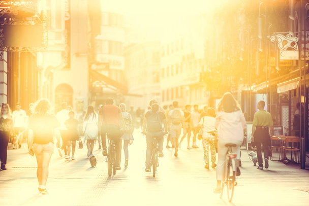 Zamazany tłum ludzi na ulicy Copova pieszych w Lublanie o zachodzie słońca. Koncepcja miejskiego stylu życia i mobilności. - Zdjęcie, obraz