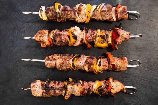ed Pork and Lamb Skewer veya Kebob with Red and Yellow Bell Pepper and Onion on a Dark Plate Plate - Fotoğraf, Görsel