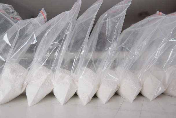 A large number of transparent sachets filled with white powder. White powder packaged in small sachets. - Photo, Image