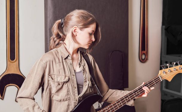 mladá krásná žena hrající na baskytaru v domácím studiu. rocková hudba. kontrola zvukového zvuku. - Fotografie, Obrázek