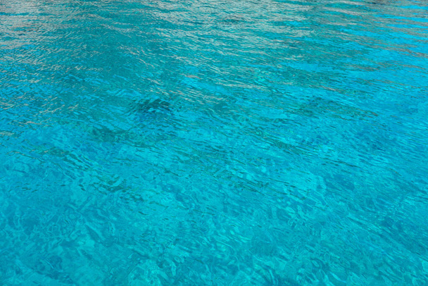 Поверхня моря бірюзово-блакитний кольоровий фон, деякі відображення. Спокійна кристально чиста вода з дрібними брижами, літні канікули в тропічному раю
. - Фото, зображення