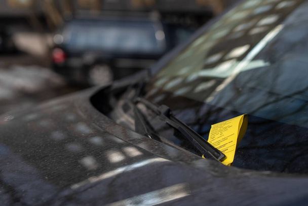Parking ticket placed under the wiper blade on the windscreen of an illegally parked car in Tallinn city center (Estonian - Kesklinn).  - Foto, Imagen