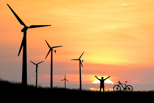 Силуэты ветряных турбин в поле на закате. - Фото, изображение