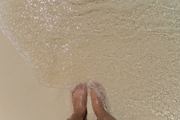 pé descalço na praia de areia com ondas suaves pela manhã. foco suave - Foto, Imagem