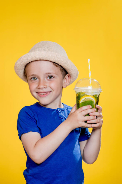 Cute boy Drink Mojito cocktail From Plastic Cup Over Yellow Studio Background. - Foto, immagini