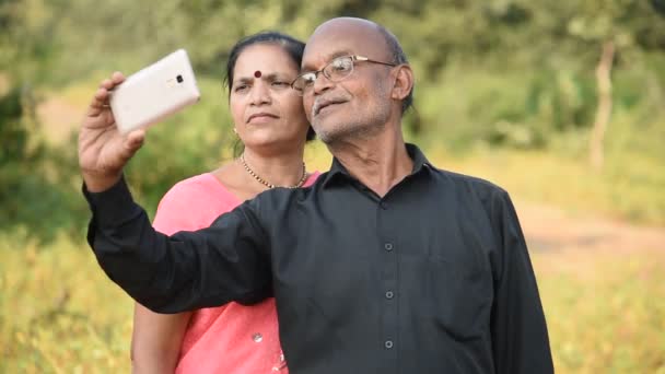 Felice coppia indiana anziana marito e moglie prendendo un selfie su smartphone, sorridendo insieme all'aperto.  - Filmati, video