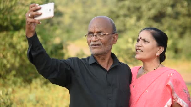 Mutlu Hintli çift karı koca akıllı telefondan selfie çekiyor, açık havada birlikte gülümsüyorlar..  - Video, Çekim