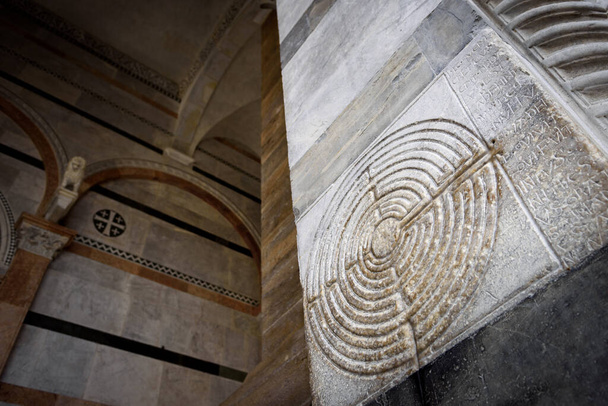 Katedra w Lucca (Toskania, Włochy). Szczegóły starożytnej słynnej kolumny labiryntu na fasadzie, ozdobione średniowiecznym labiryntem nad białym marmurem kościoła  - Zdjęcie, obraz