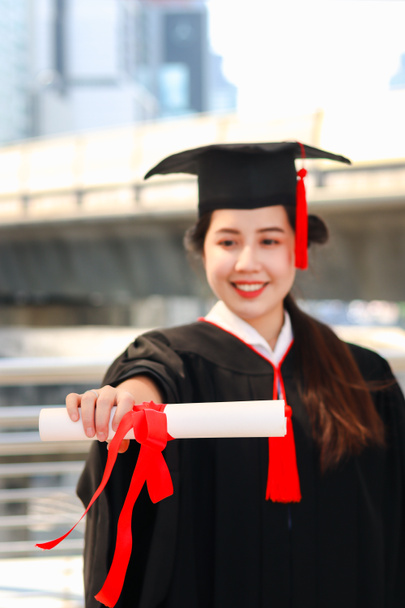 Feliz sorrindo estudante graduado, jovem bela mulher asiática aquecendo chapéu acadêmico quadrado e dando certificado para a câmera, celebrando a educação bem sucedida no dia da formatura início quando terminou os estudos para a universidade ou faculdade. - Foto, Imagem