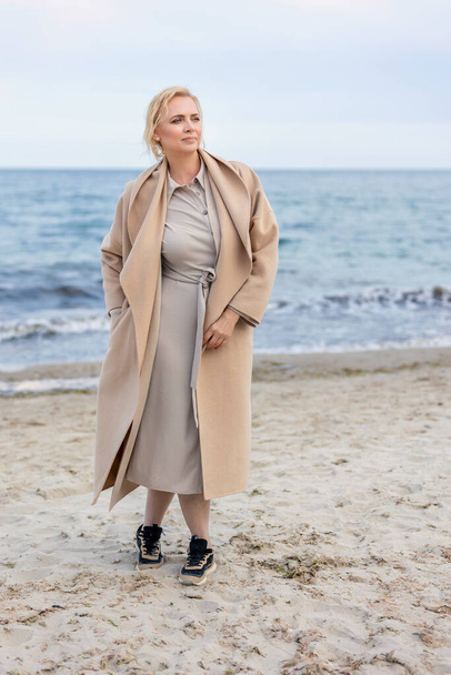 Woman in coat by the sea - Foto, afbeelding