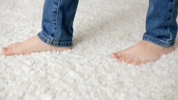 Szoros kép a kis csupasz gyerek lábak séta puha fehér szőnyegen - Felvétel, videó