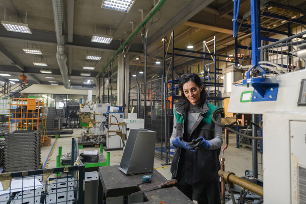 a woman working in a modern metal factory assembles parts for a new machine. High quality photo - Foto, immagini