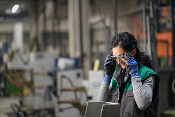 Woman worker wearing safety goggles control lathe machines to drill components. Metal lathe industrial manufacturing factory. High quality photo - Foto, immagini