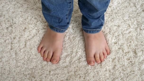 Lindos pies de niños pequeños de pie en la alfombra blanca suave y dedos de los pies en movimiento - Imágenes, Vídeo