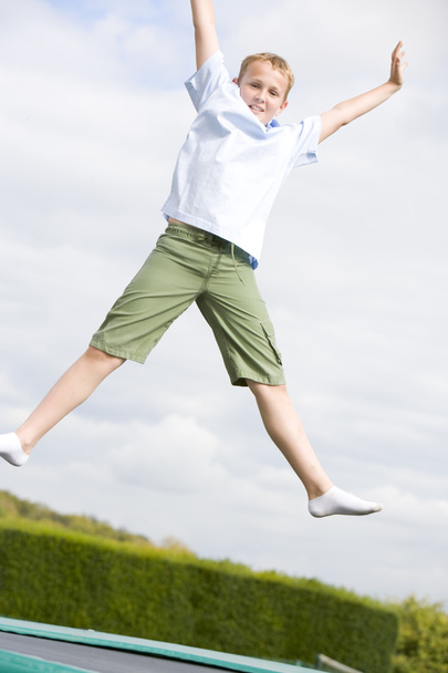 Young boy jumping on trampoline smiling - Photo, image