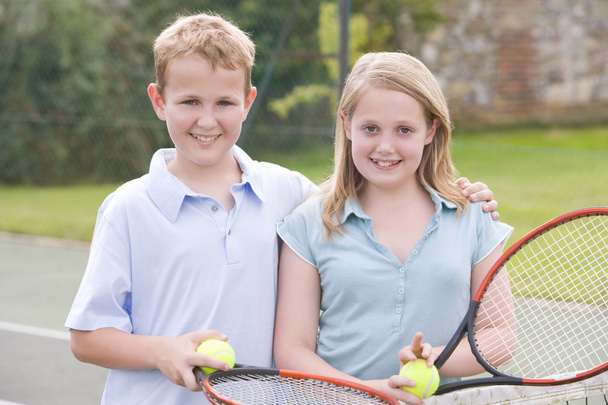 Two young friends with rackets on tennis court smiling - Φωτογραφία, εικόνα