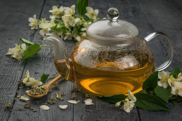 Siyah ahşap bir masada cam bir çaydanlık yasemin çayı. Sağlığın için iyi olan canlandırıcı bir içecek.. - Fotoğraf, Görsel