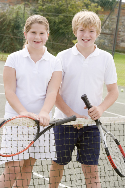 Two young friends with rackets on tennis court smiling - Foto, Imagem