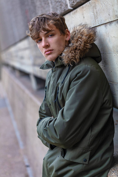 Male young adult teenager wearing a parka jacket outside in modern an urban city environment - Фото, зображення