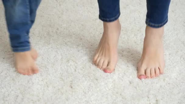 Close-up van blootsvoets moeder met kleine zoon springen en spelen op zacht wit tapijt - Video