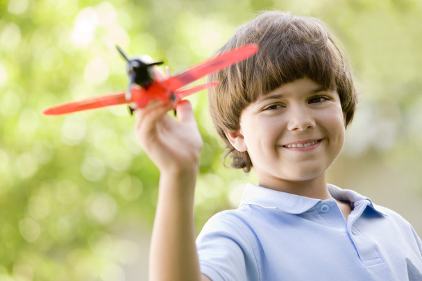 Young boy with toy airplane outdoors smiling - Foto, Imagem