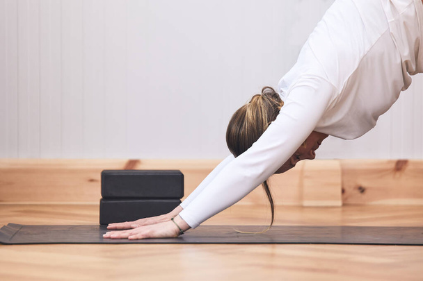 vrouw doet een moeilijk vliegtuig stretching op een yoga mat met kopieerruimte - Foto, afbeelding