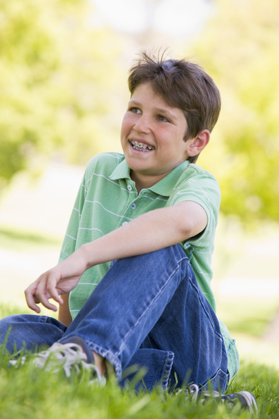 Young boy sitting outdoors smiling - Fotografie, Obrázek