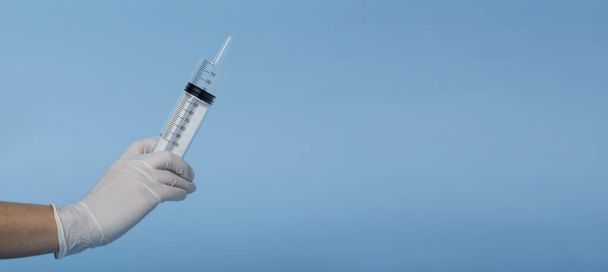 Закрыть медицинскую концепцию 100 мл медицинского шприца в руке врача изолированы на синем фоне. Баннер - Фото, изображение