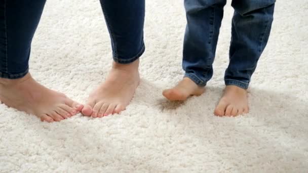 Closeup of funny barefoot mother with son dancing on soft white carpet - Footage, Video