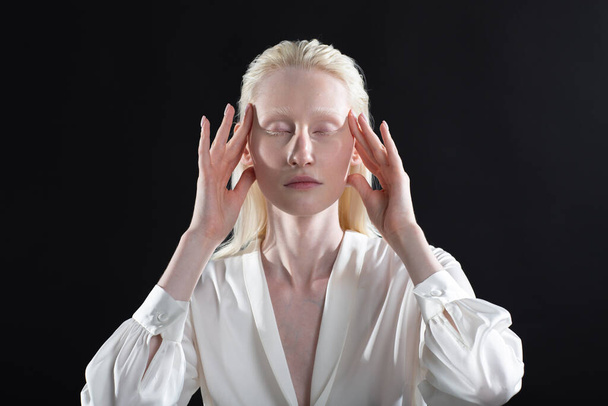 Jovem mulher albina loira fazendo construção facial ginástica facial auto massagem e exercícios de rejuvenescimento no fundo preto - Foto, Imagem