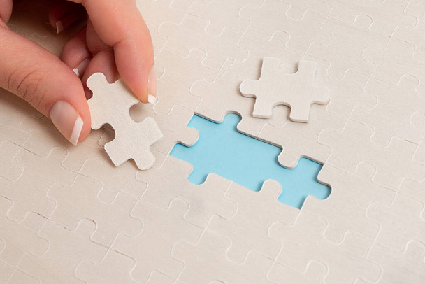 Close-Up White Jigsaw Pattern Puzzle Piezas que se conectarán con faltante última pieza colocada en un fondo plano con diferentes accesorios de textura y papel - Foto, Imagen