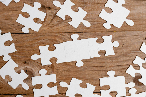 Close-Up White Jigsaw Pattern Puzzle Pieces To Be Connected With Missing Last Piece Positioned On A Flat Lay Background With Different Texture And Paper Supplies Accesories - Photo, Image