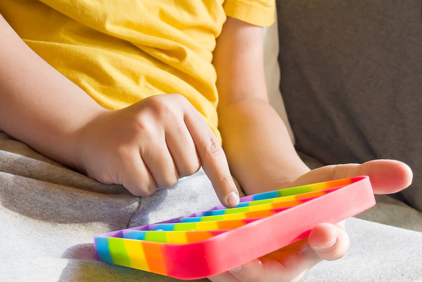 kleurrijke anti-stress zintuiglijke fidget duwen pop het speelgoed in handen van kinderen. - Foto, afbeelding