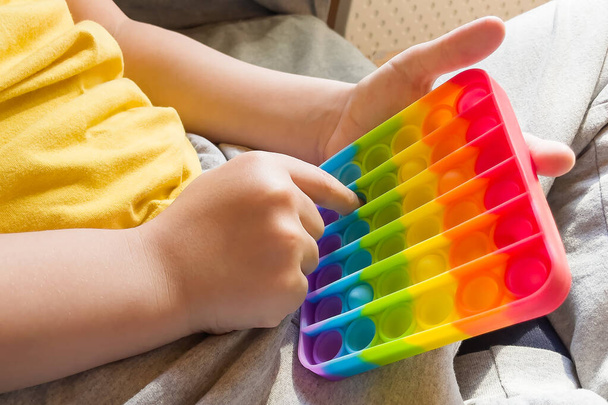 красочный антистрессовый сенсорный трепет толкать его игрушку в детские руки. - Фото, изображение